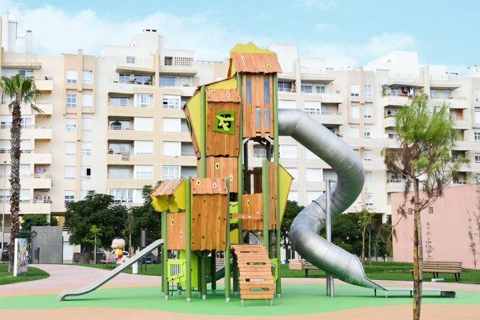 Öffentliche Spielanlagen – eibe Spielanlage mit Rutsche vor einem Wohnkomplex.
