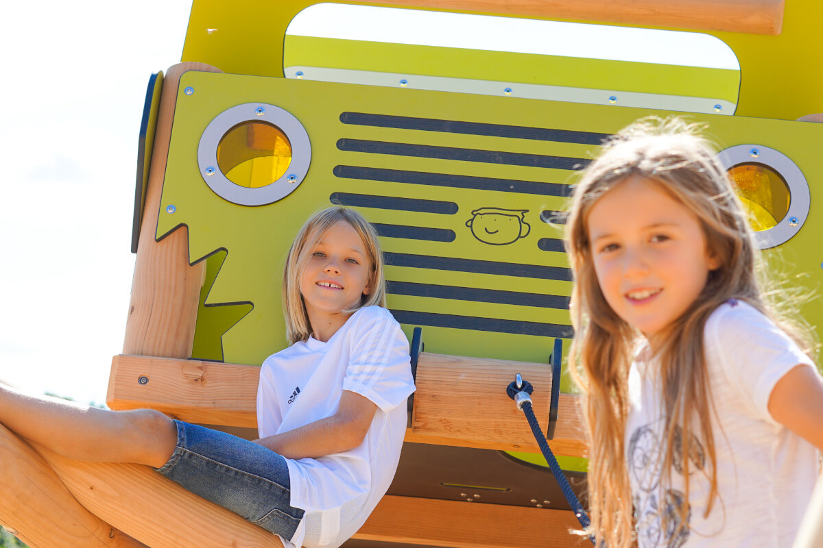 Zwei Mädchen sitzen auf öffentlichen Spielanlage von eibe.