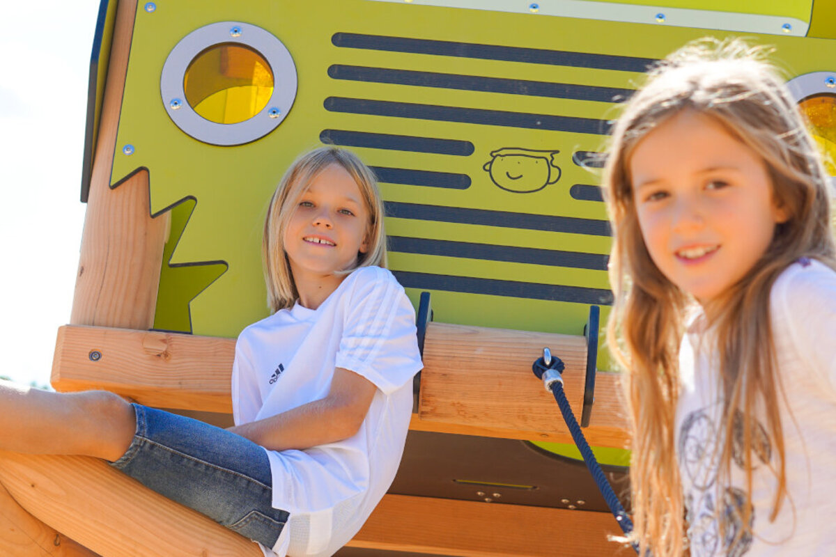 Zwei Mädchen sitzen auf öffentlichen Spielanlage von eibe.
