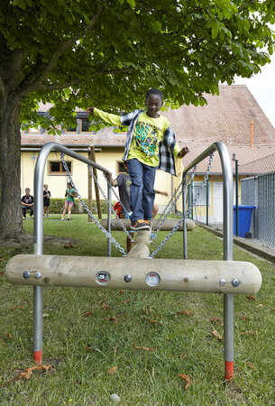 Schulhofplanung – Schüler balanciert über eibe Spielgerät auf dem Pausenhof.
